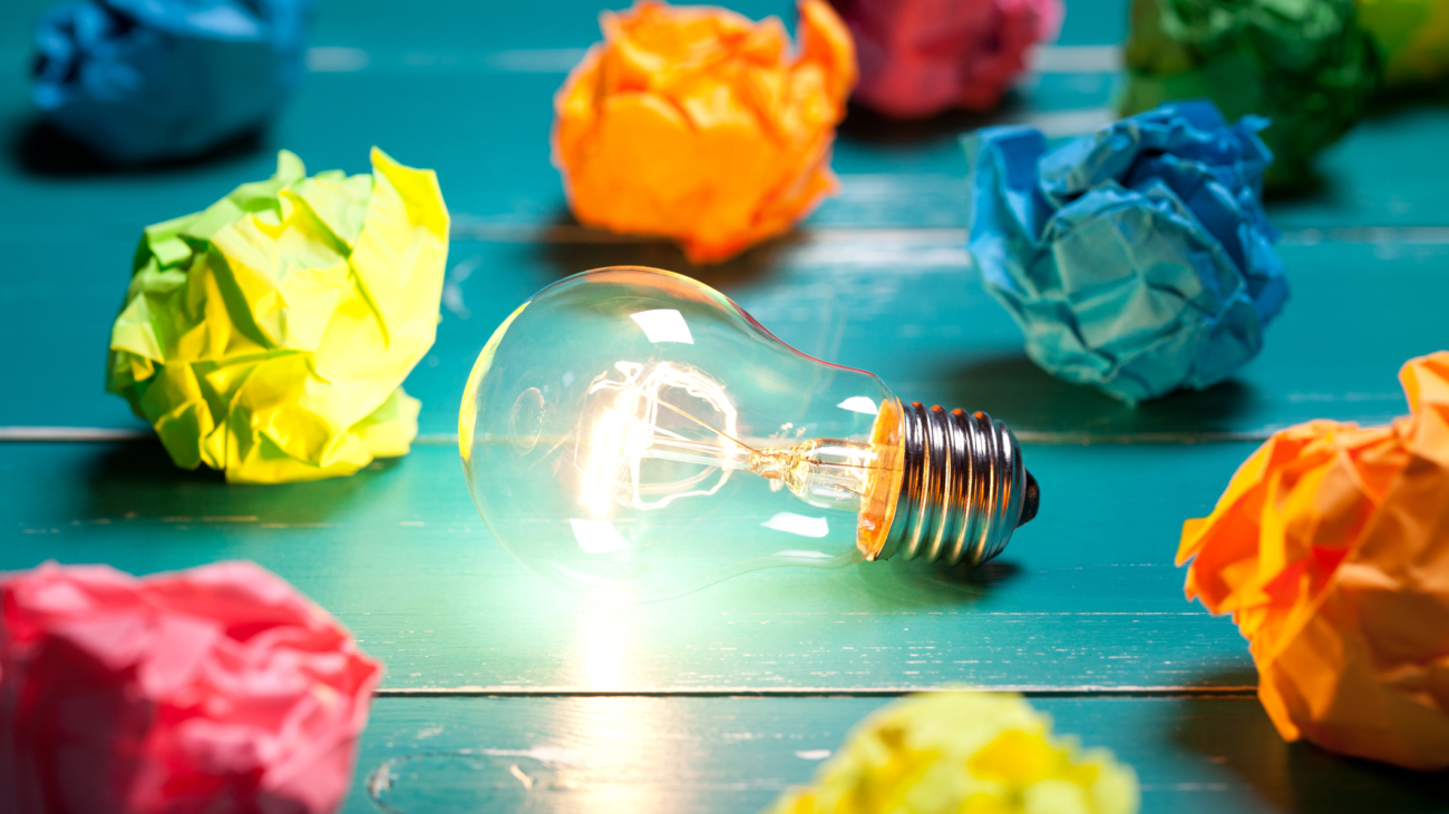 Incandescent bulb and colorful notes on turquoise wooden table. This file is cleaned and retouched.